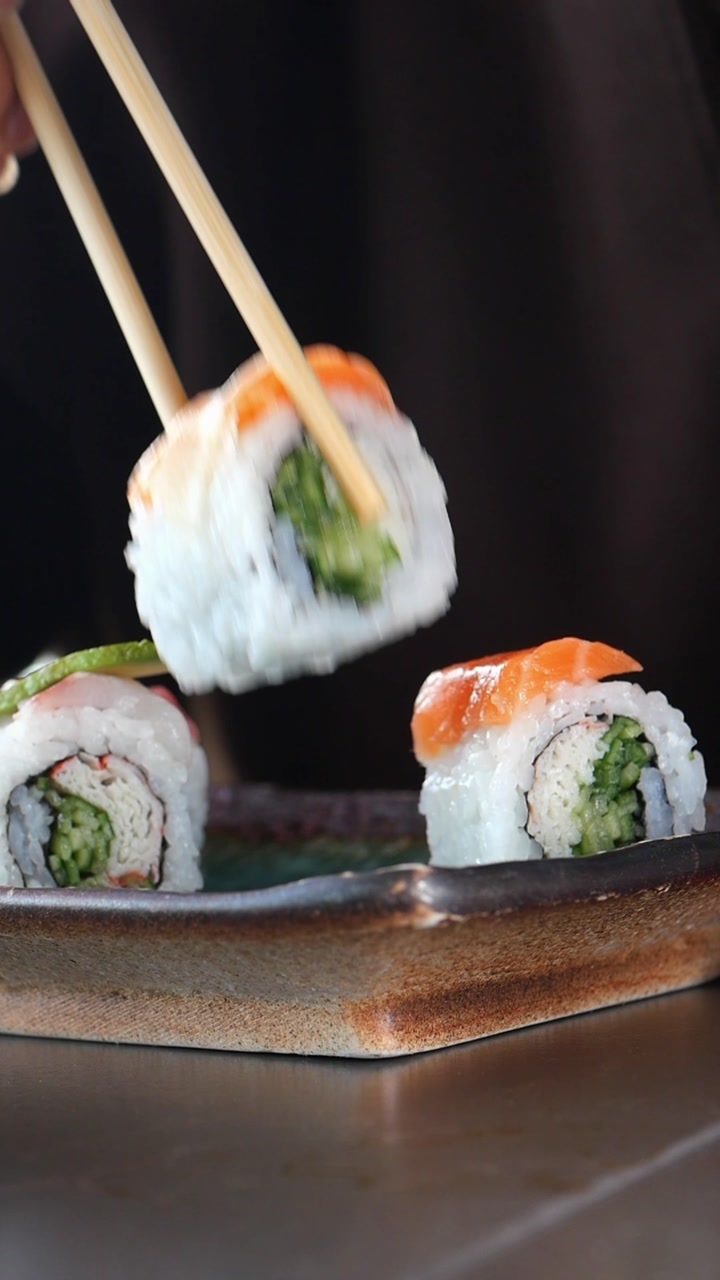 Chopsticks Picking Up Fresh Salmon Sushi Roll