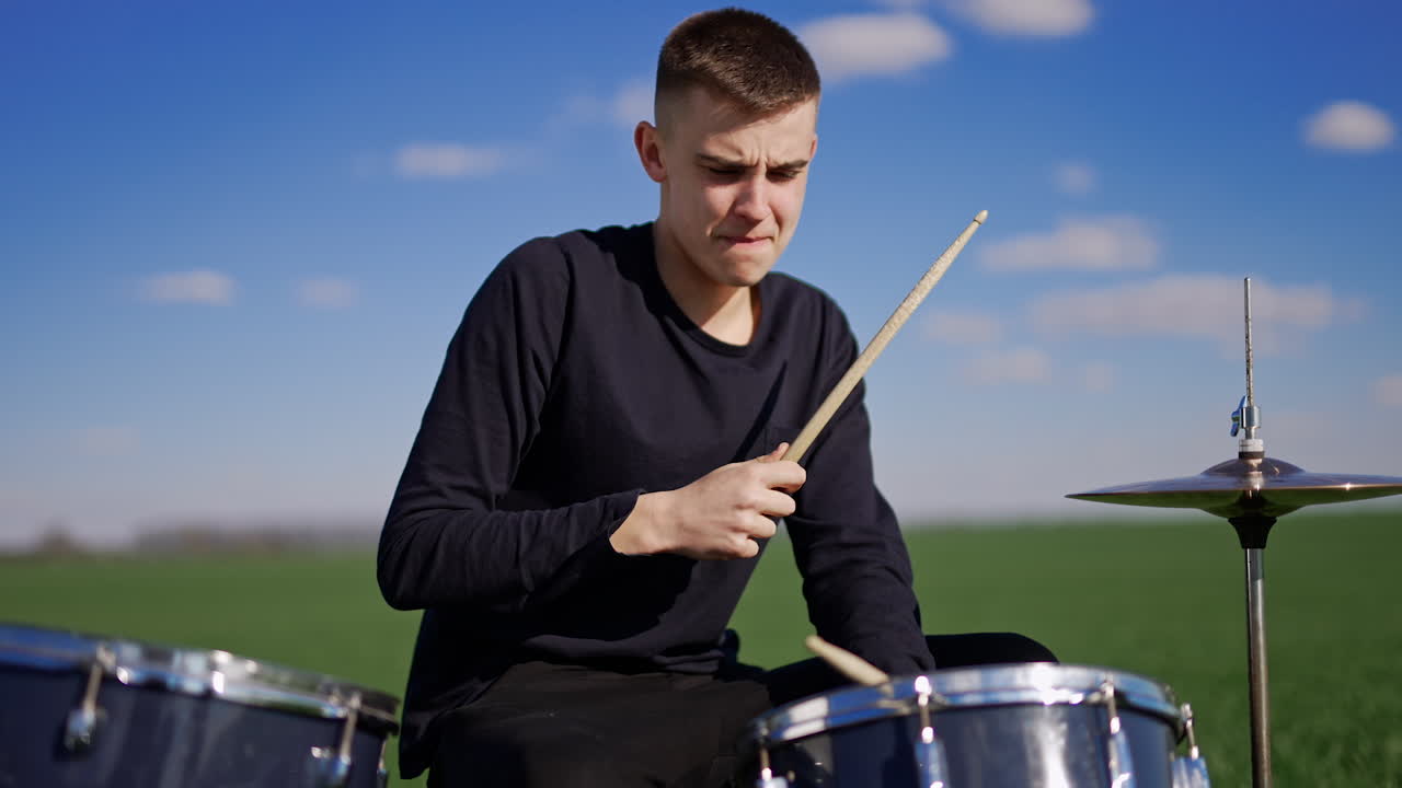 Teenager Playing Drums in a Field