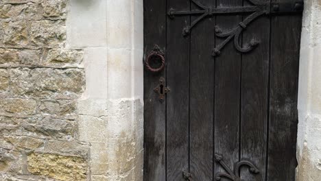 antique black wooden door of holy trinity church in headington quarry, oxfordshire, england