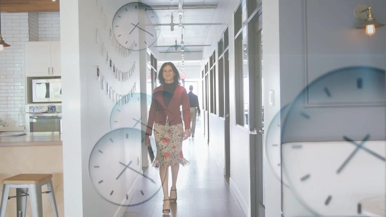 Mujer y hombre caminando por el pasillo de la oficina, relojes translúcidos apareciendo gradualmente, oscureciendo la vista mientras se desplazan.