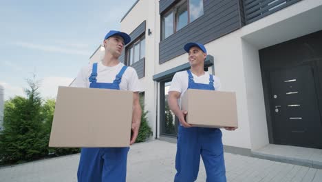 two young workers of removal company deliver boxes to a customer's home