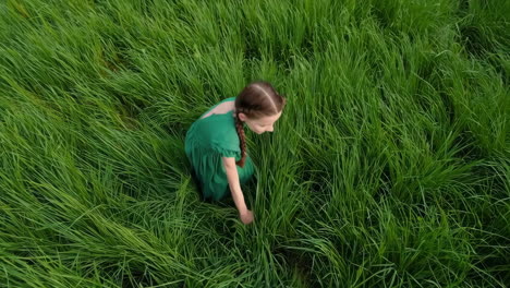 girl in a green dress sitting in a field of grass