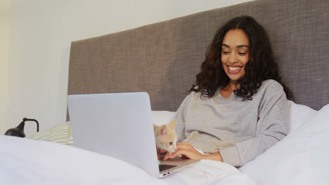 Mujer-Feliz-Usando-Su-Computadora-Portátil-Mientras-Está-Sentada-En-La-Cama-Con-Su-Gato-4k-4k