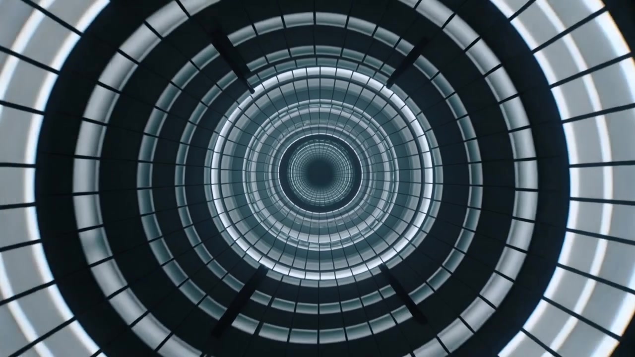 Pulsing LEDs revealing multi-ring shaft deepening tunnel at atrium center, showing radial dividers