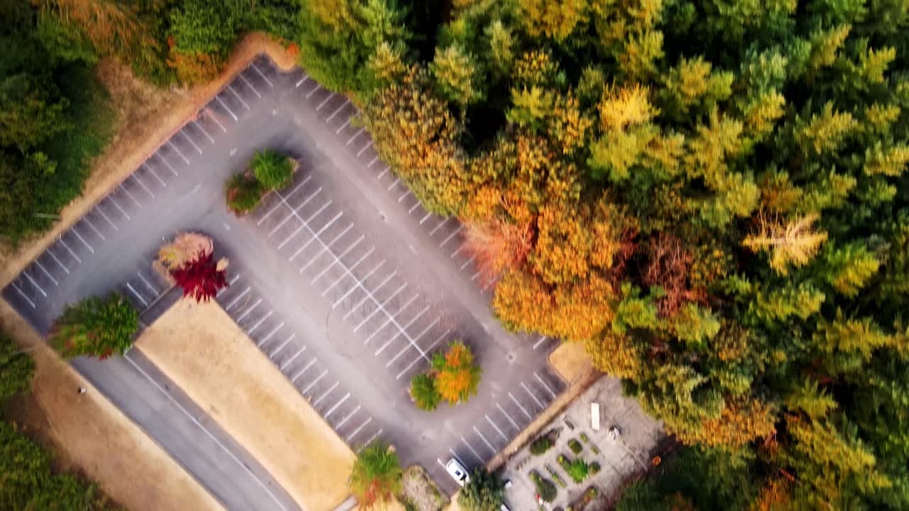 vista aérea de drones sobre automóviles estacionados en un estacionamiento a lo largo de un exuberante bosque verde a lo largo de un terreno montañoso en snoqualmie, washington, estados unidos durante el día