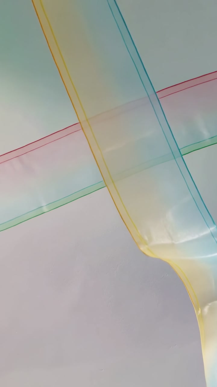 Vertical video: Gliding sheer fabric ribbons crossing pale wall in five frames, revealing seams