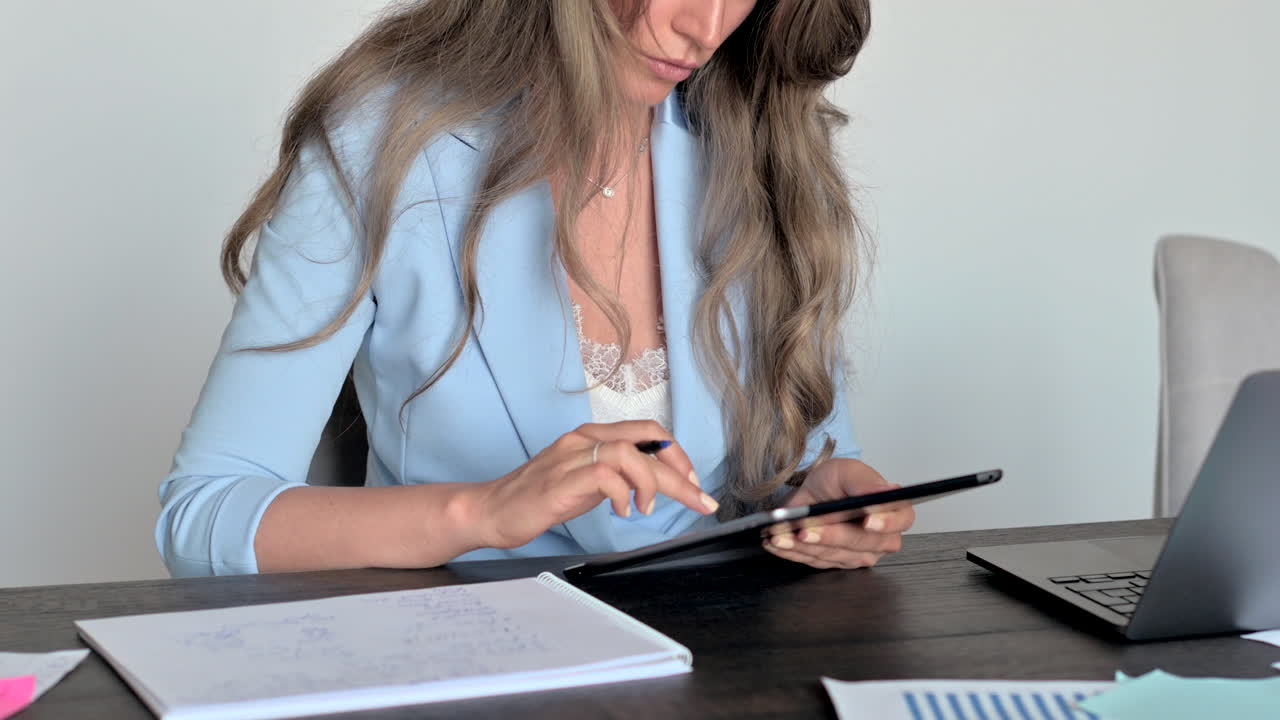 Woman in blue blazer working on a tablet at a desk in an office