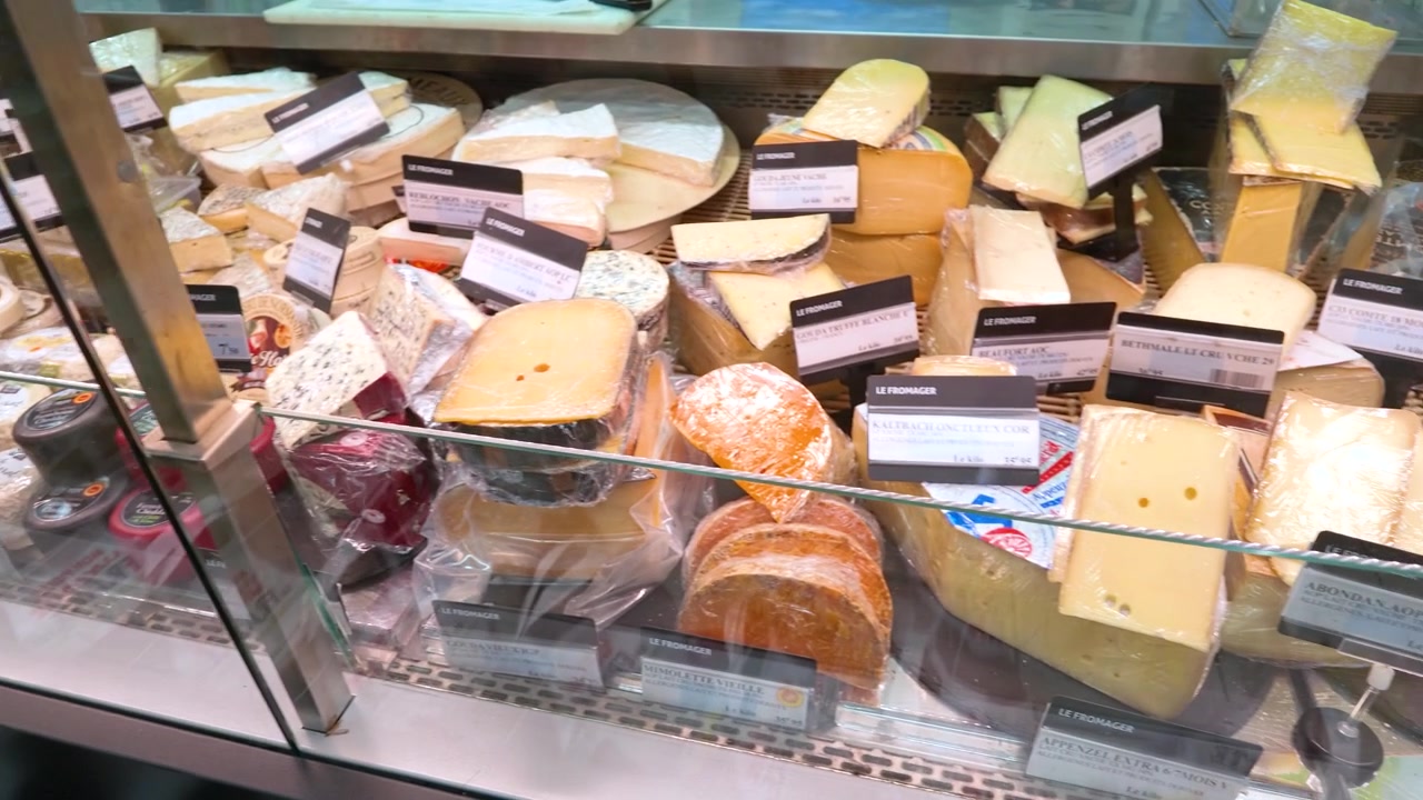 Kameran panorerar över ett urval av franska ostar inuti en kyld glasmonter