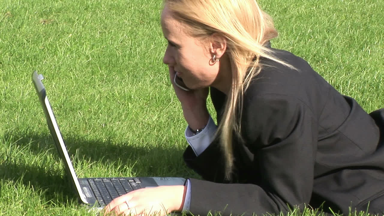Woman lying on grass using laptop computer