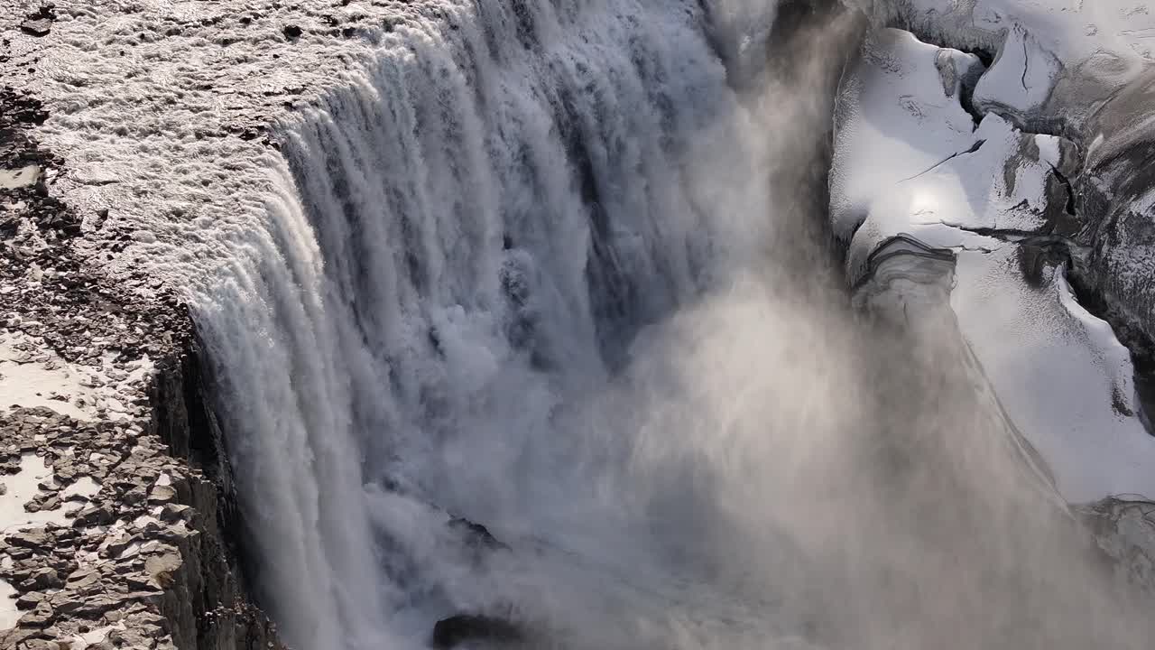 Snow dusted cliffs frame Dettifoss waterfall’s thundering plunge through Iceland’s icy terrain