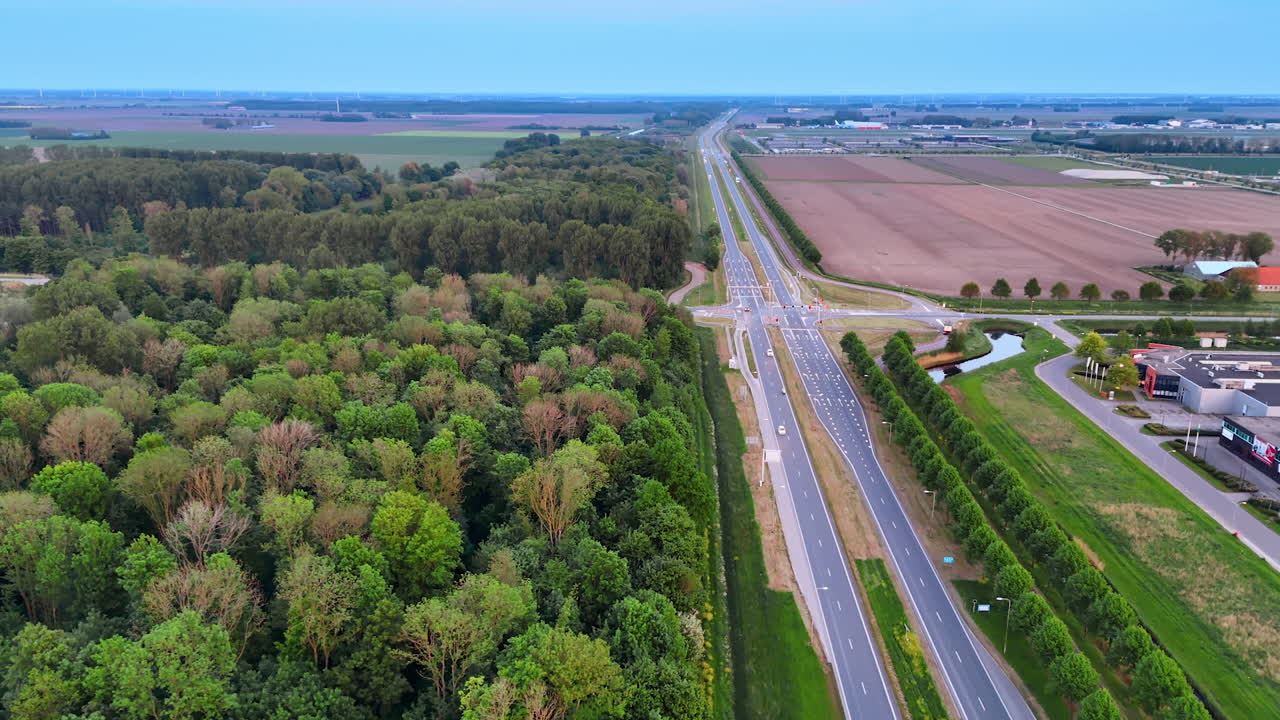 Spring fields by the forest. A landscape showcases a highway lined with lush greenery and expansive agricultural fields under a clear sky in spring