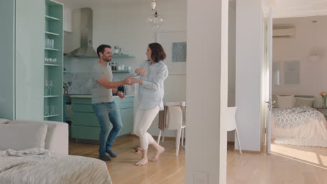 Feliz-Pareja-Joven-Bailando-En-Casa-Disfrutando-Del-Baile-Juntos-Divirtiéndose-Celebrando-La-Relación