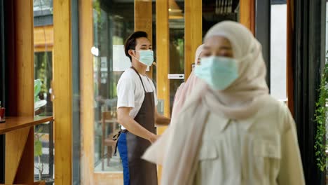 in the midst of the covid-19 pandemic, halal food employees are checking the temperature of a muslim woman who enters the restaurant to drink and eat after ramadan.