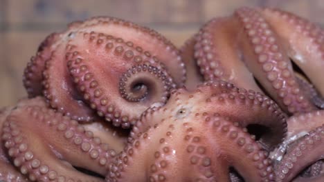 group of hot boiling octopus  freshly prepared spinning round on wooden table. kitchen blur background