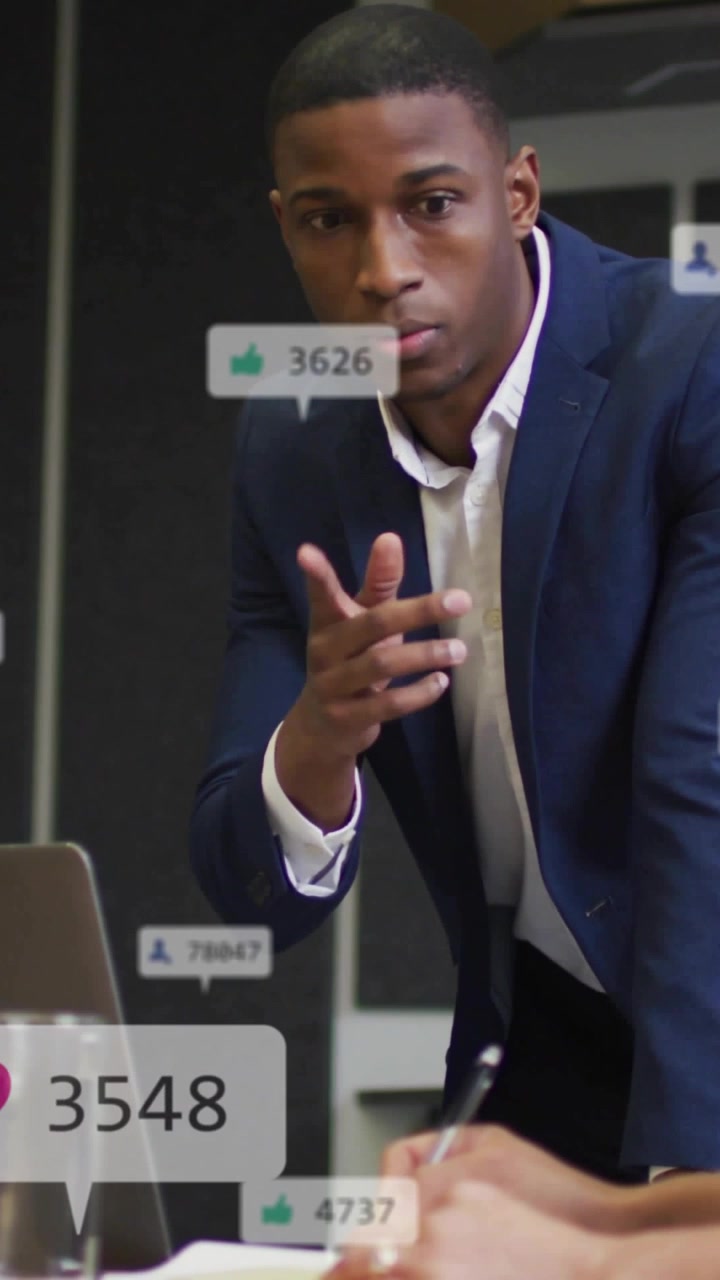 Vertical video: Leader leaning over table gesturing causing likes to rise to show business metrics