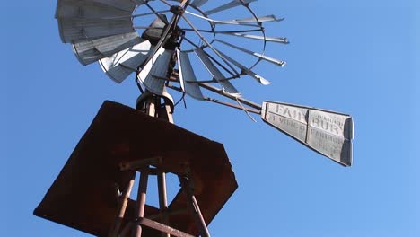 panup from the base of a windmill to the blades turning in the wind