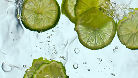 citrus pieces floating water in super slow motion close up. lime dropped liquid.