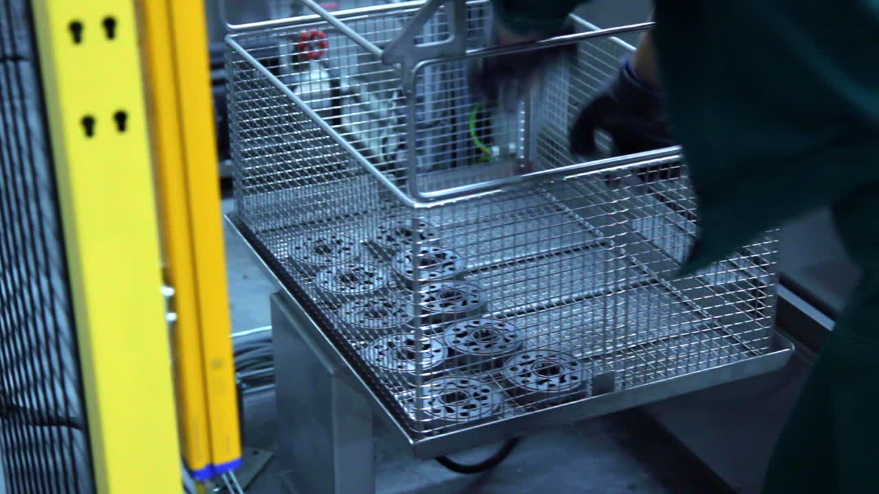Worker taking finished parts off assembly line at factory. Machine parts
