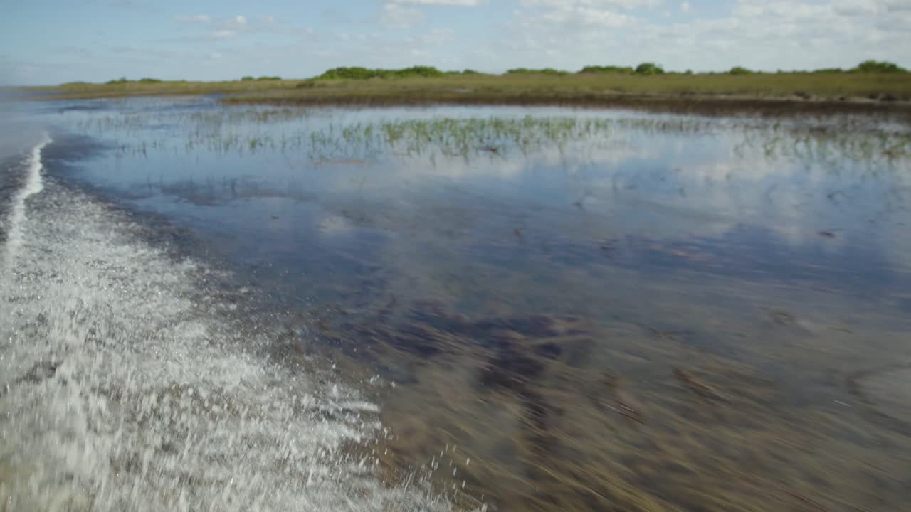 Slow motion footage of the Florida Everglades taken from an airboat. Wide scenic views of wetlands, waterways, and tropical vegetation from the water level