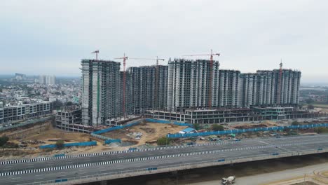 aerial drone shot offering a panoramic view of an under-construction site near dwarka expressway, with surrounding roads and developing infrastructure.
