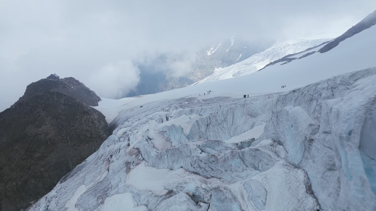 Aerial revealing massive Steingletscher glacier with deep blue crevasses, surrounded by rocky mountains under cloudy sky, Susten Pass, Swiss Alps, Switzerland