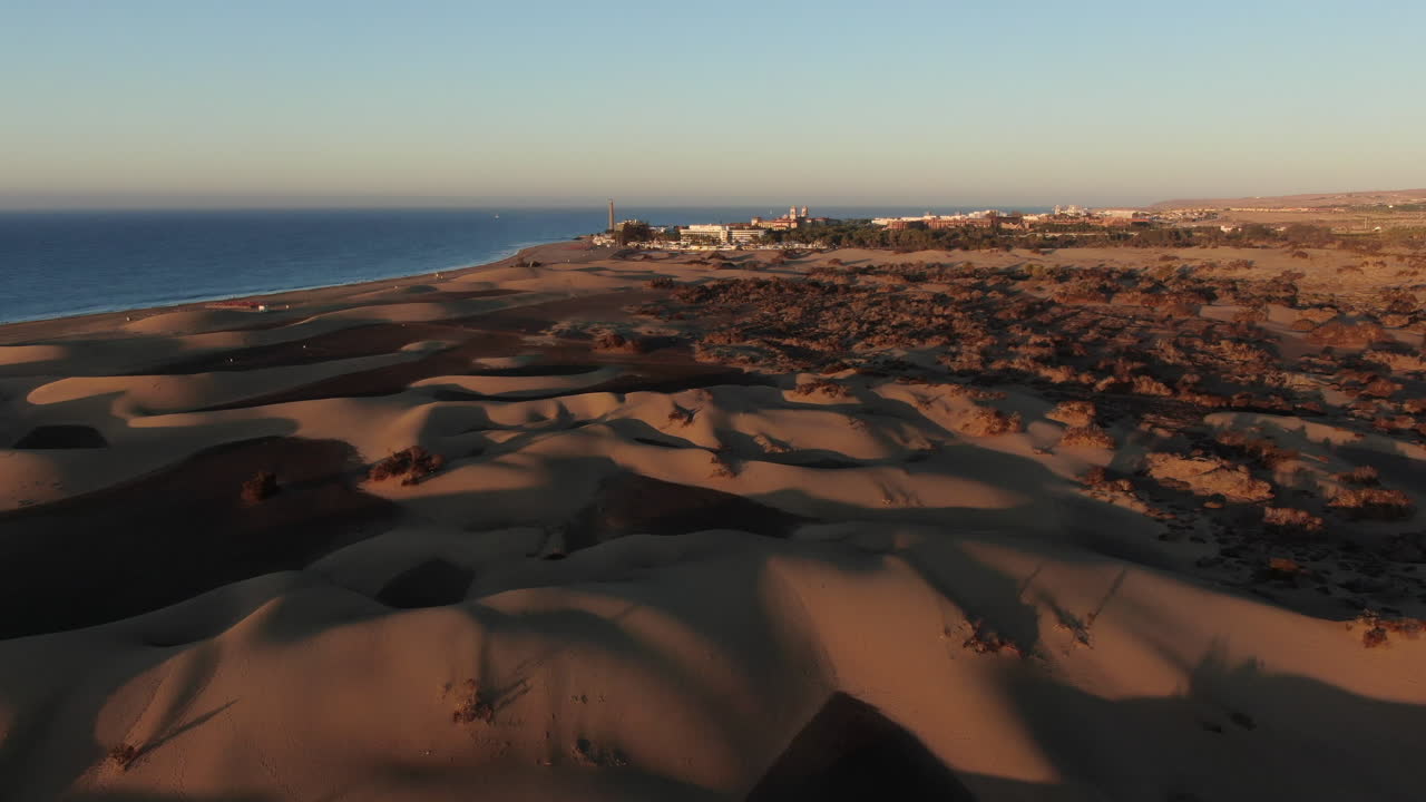 drone volando bajo sobre una playa de arena, avanzando lentamente durante la puesta de sol
