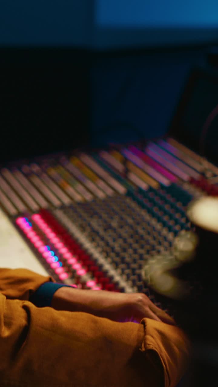 Sound Engineer Adjusting Faders on Audio Mixing Console