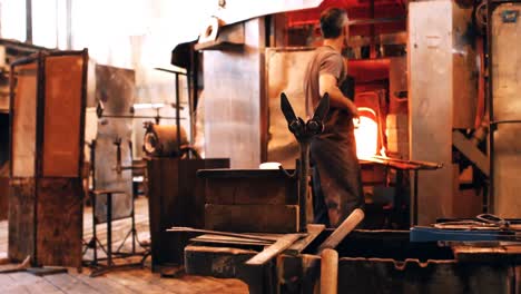 glassblower reheating a piece of glass in furnace