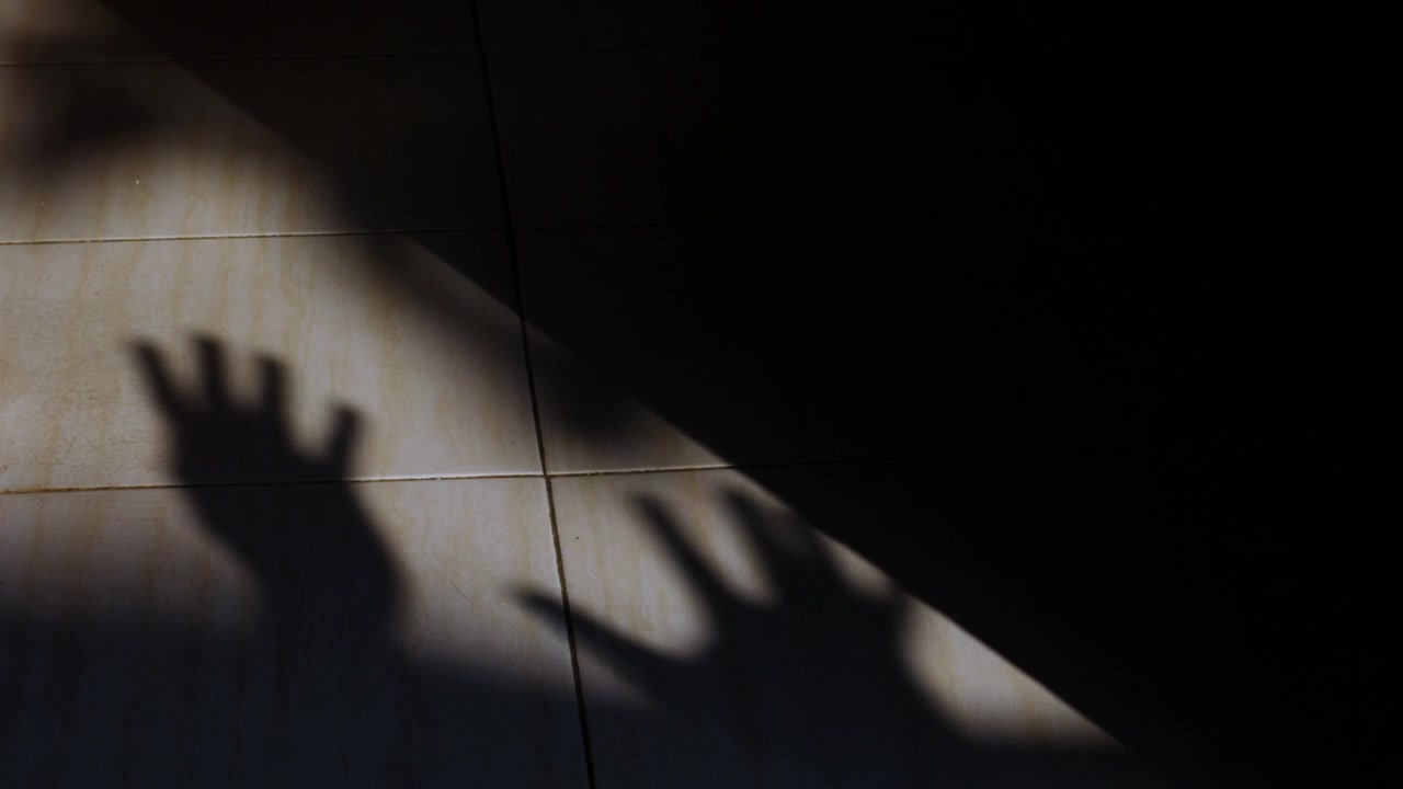 Silhouette of Praying Hands on a Sunlit Tile Floor