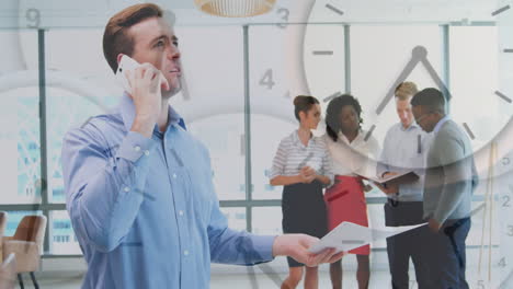 Animation-of-clocks-moving-over-diverse-colleagues-talking-on-smartphone-and-discussing-in-office