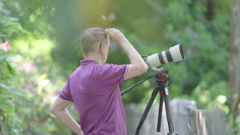 videographer checks his surroundings and uses camera with lens on tripod