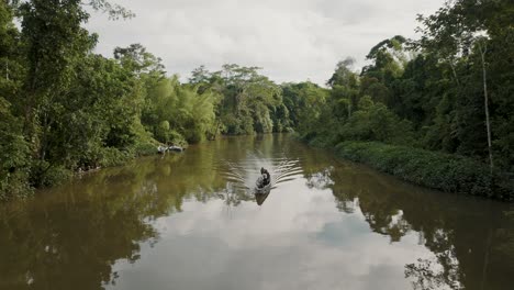 Toma-Aérea-De-4k-De-Drones-Moviéndose-Con-El-Velero-En-El-Río-Amazonas-Y-El-Bosque-Tropical-En-Ambos-Lados-Del-Río