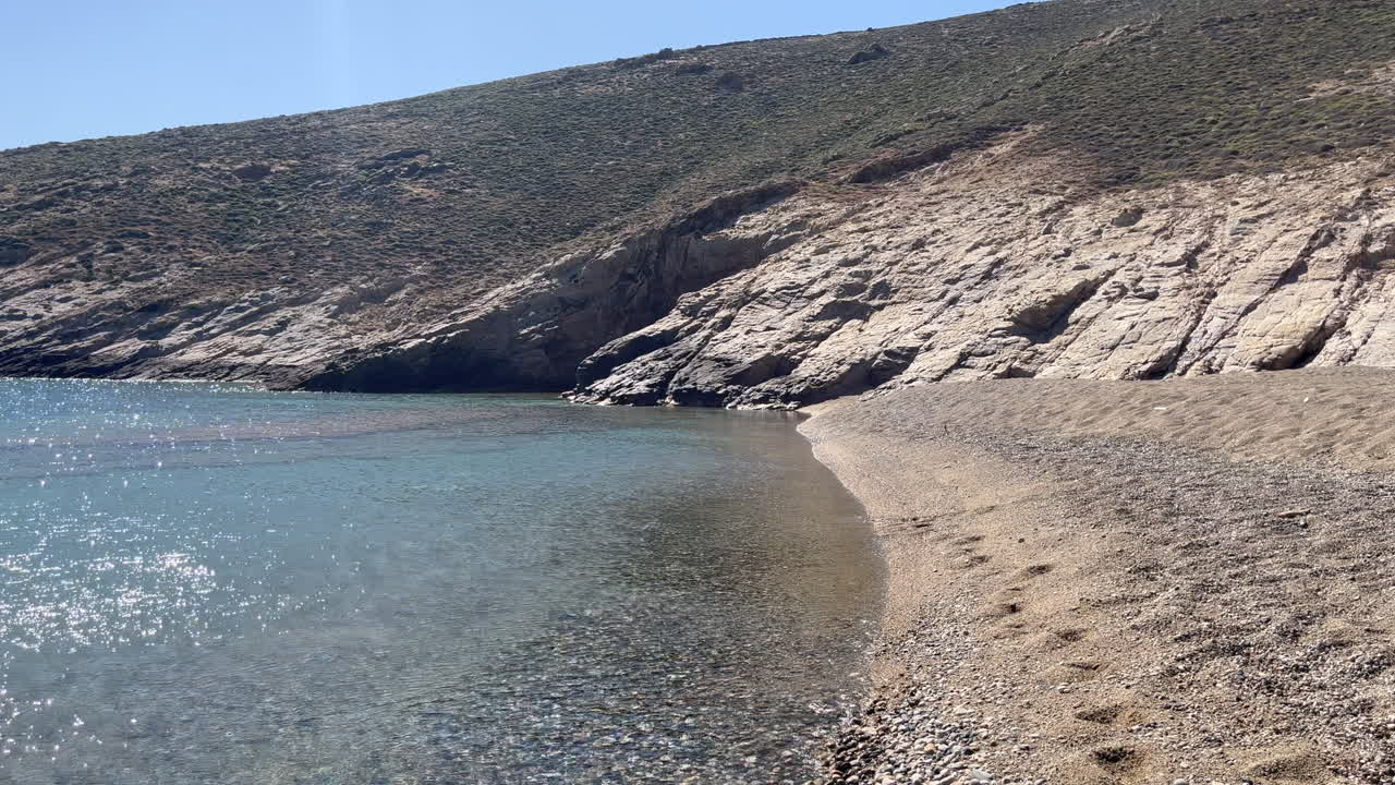 Peaceful waves roll gently onto Fokos Beach on the Greek island of Mykonos. Ideal for relaxation, travel edits, or ambient nature scenes