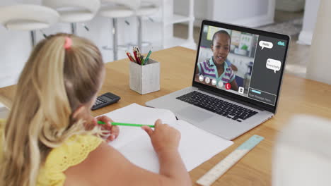 schoolgirl using laptop for online lesson at home, with her colleague and web chat on screen