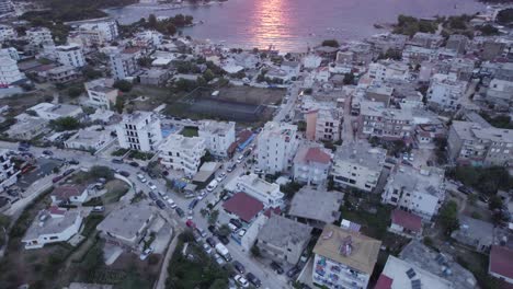 drone flyover ksamil downtown revealing breathtaking sunset over ionian seascape, tilt up shot