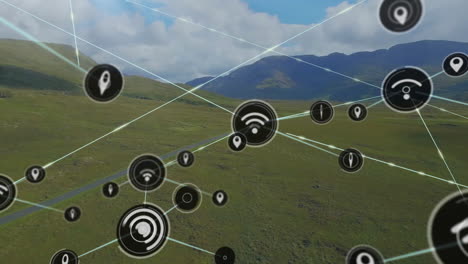 animación de iconos conectados sobre vista aérea de tierras verdes y montañas contra un cielo nublado