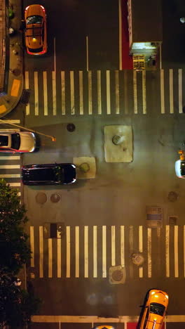 descending view over the busy crossroads of new york. well-lit street with numerous moving cars. top view. vertical video