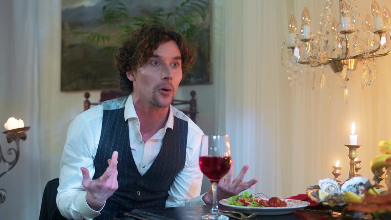 Man in Vest Expressively Talking at a Candlelit Dinner