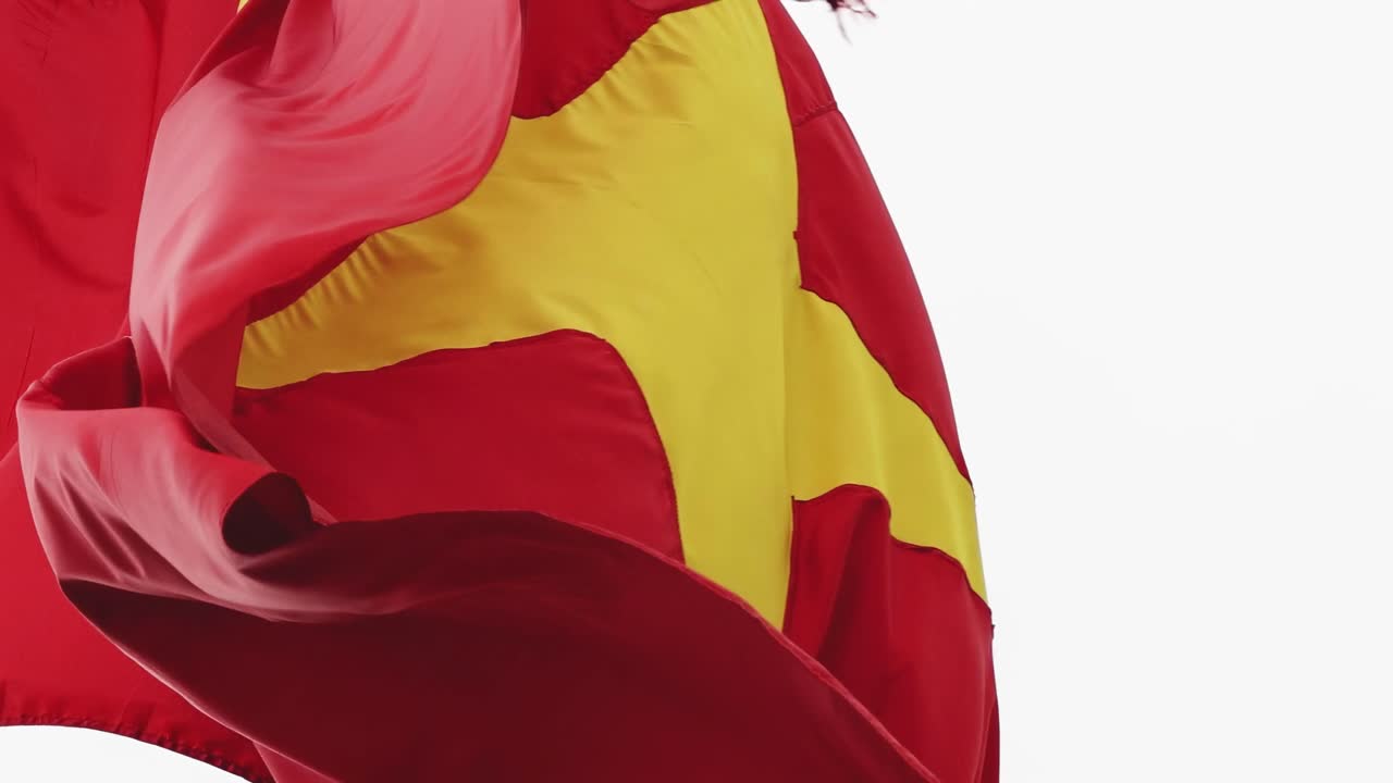 Detailed view of red fabric featuring a prominent yellow star, gently moving in the breeze.