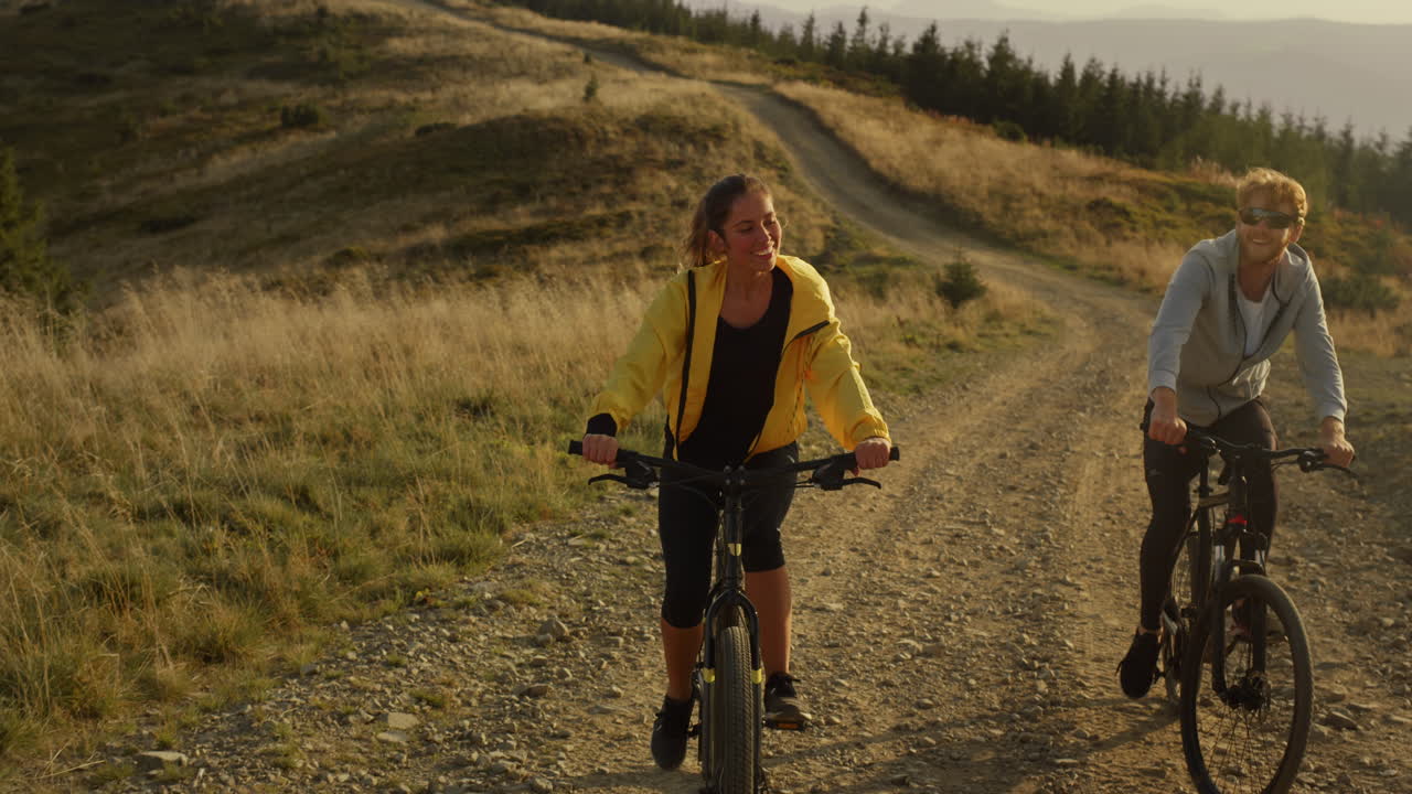 Woman and man cycling on mountain road