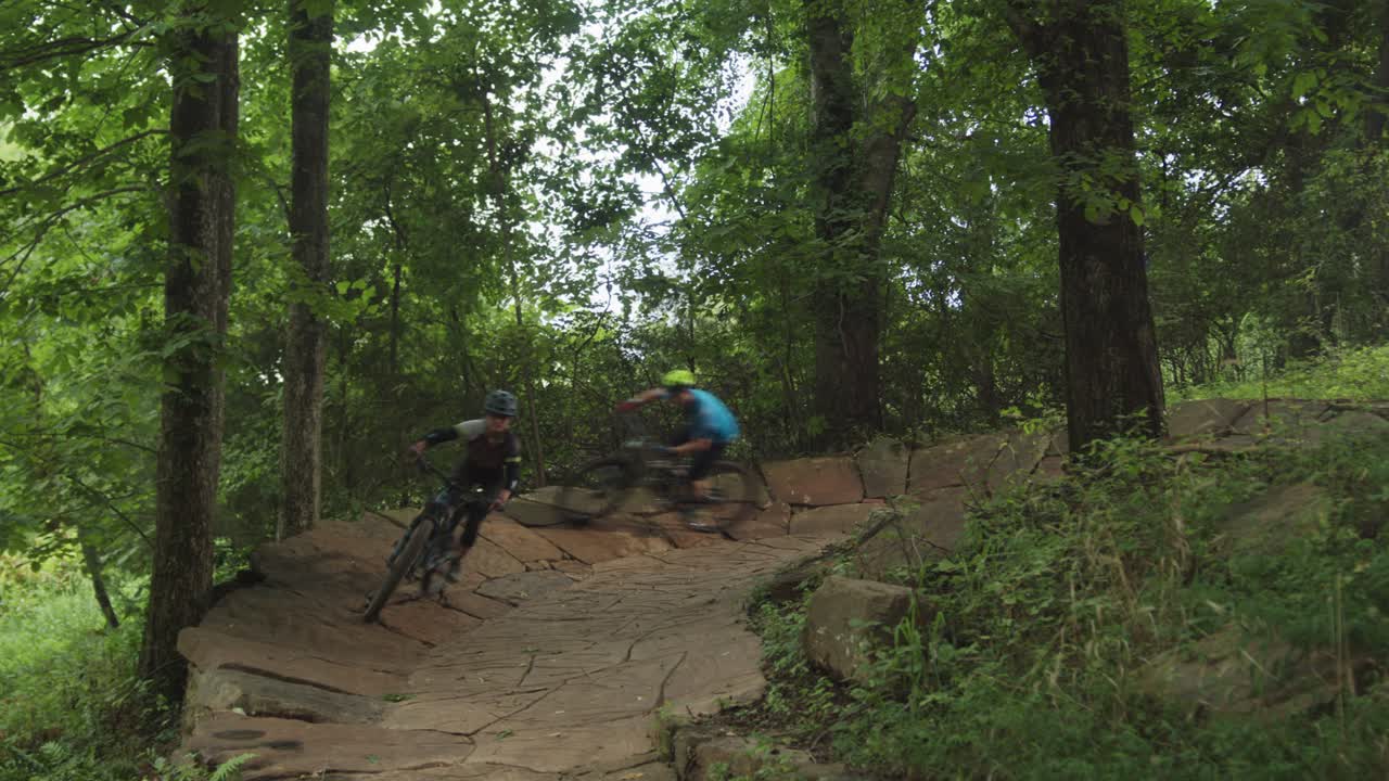 dos personas en bicicleta a través de un bosque en un sendero
