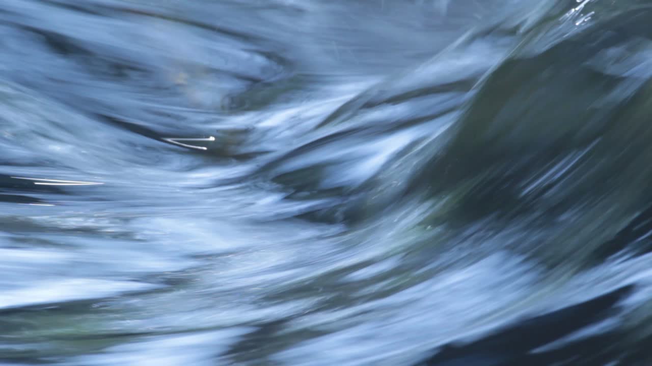 Blue river water stream detail with a swirl form going upwards