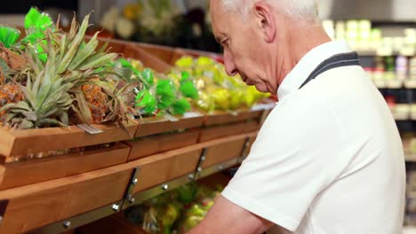 Senior-worker-stocking-the-vegetables-in-supermarket