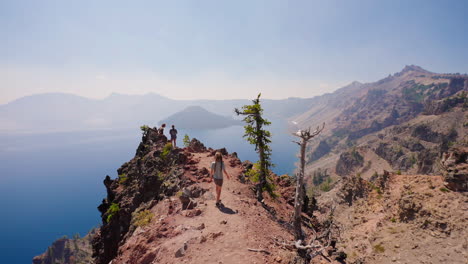 hikers on a mountain ridge overlooking a vast lake and mountain range
