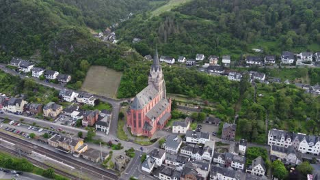 beautiful red church of our lady in medieval oberwesel town, germany amid lush hills and houses