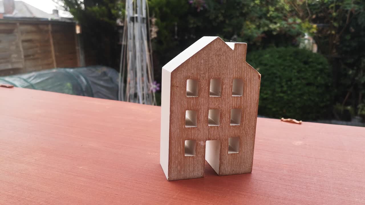 Piccolo ornamento a forma di casa in legno in giardino, idea concettuale di recessione dei mutui