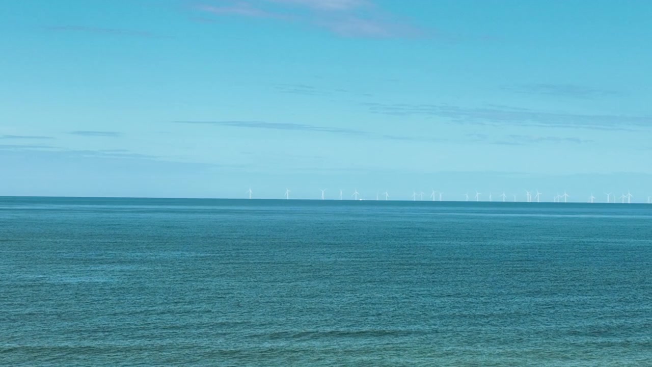 Ripresa aerea panoramica di un parco eolico offshore all'orizzonte del Mar Baltico blu. Perfetto per concetti di sostenibilità, energia rinnovabile e tecnologia ecologica