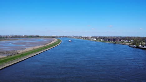 Barco-De-Carga-Cruzando-En-El-Río-Norte-Pasando-Por-La-Isla-Natural-Sophiapolder-En-Hendrik-ido-ambacht,-Países-Bajos