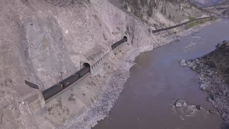 tren de vagones de tolva abierta transportar mineral a través de túneles del cañón del río
