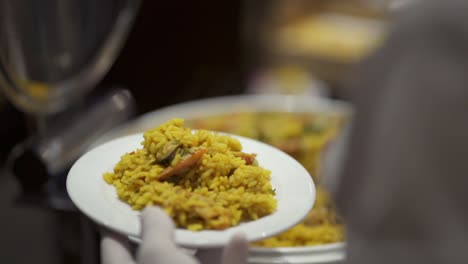 una paella siendo servida delicadamente en un plato en un buffet - de cerca